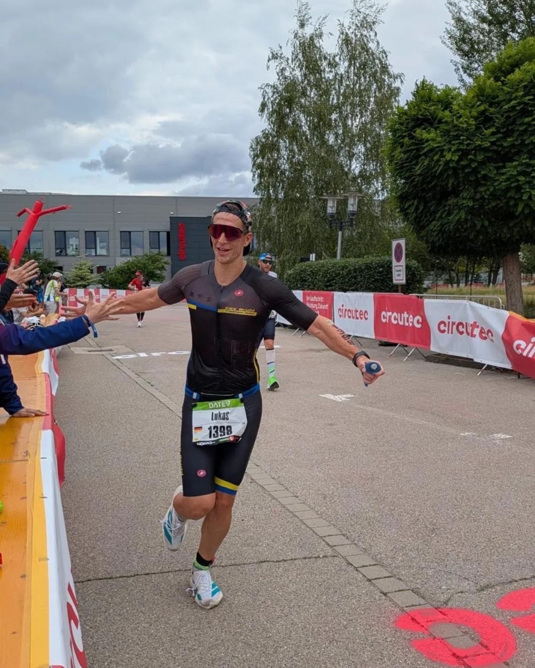 Lukas Widera vom PSV Brühl Triathlon Team mit Startnummer 1398 läuft im Zielbereich der Challenge Roth 2026 und klatscht mit Zuschauern ab