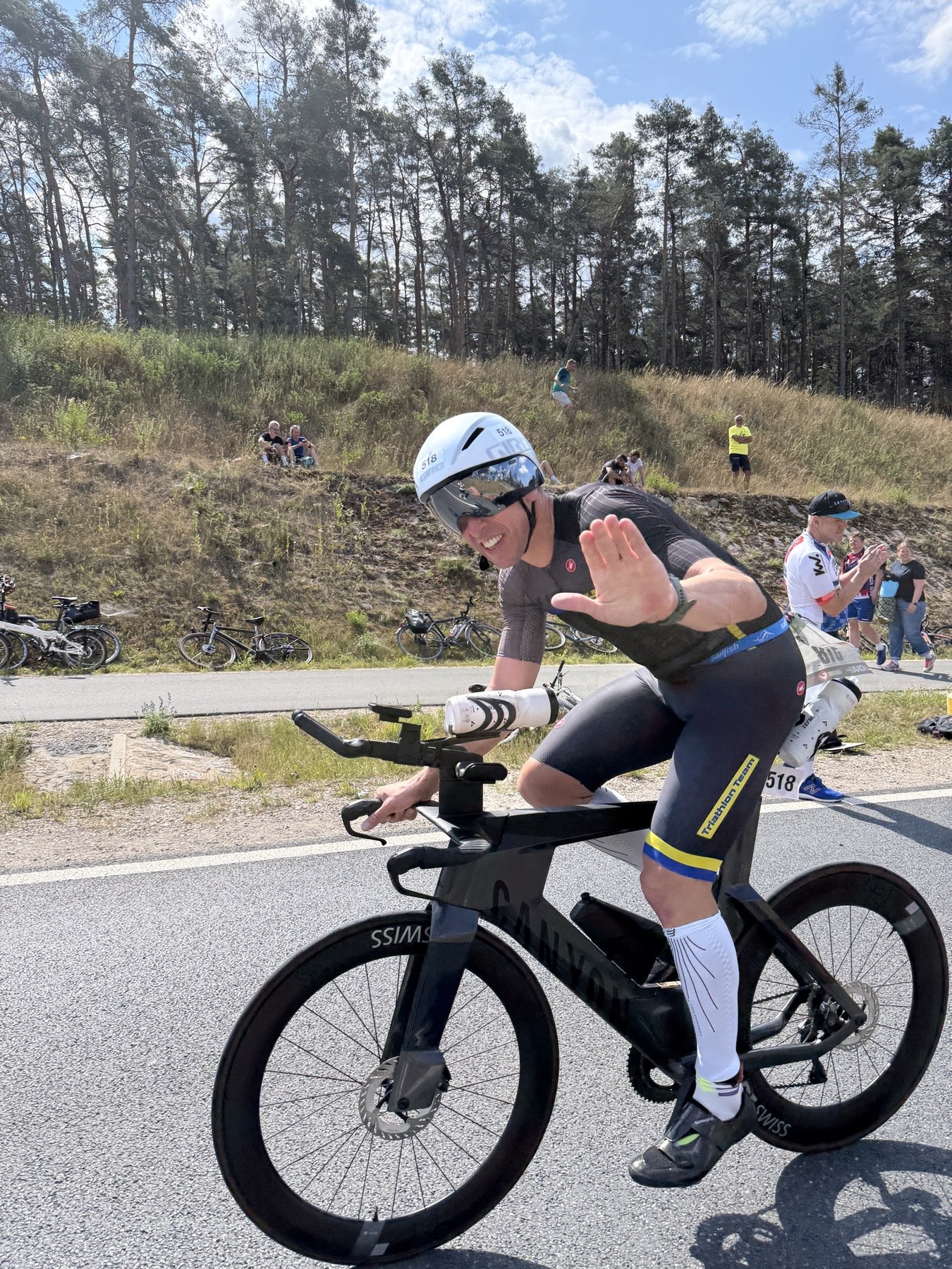PSV-Athlet Simon Widera mit Startnummer 518 lächelt und hebt die Hand – auf dem Canyon-Zeitfahrrad bei der Challenge Roth 2026