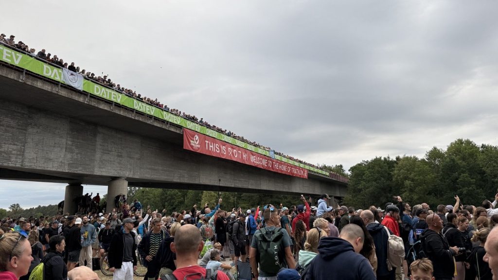 Menschenmassen unter der DATEV-Brücke mit dem Banner „THIS IS ROTH! Welcome to the home of Triathlon“ bei der Challenge Roth 2026