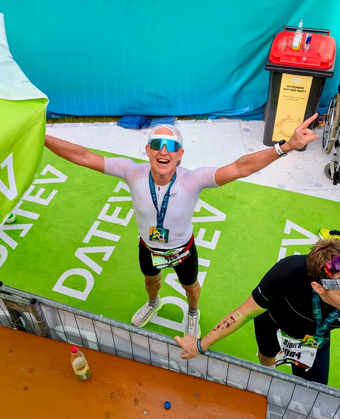 Walter Schaaf vom PSV Brühl Triathlon Team steht mit ausgebreiteten Armen und der Finisher-Medaille im Zielbereich der Challenge Roth 2026