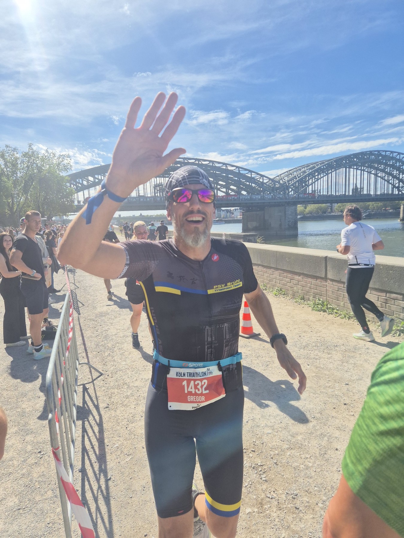 Gregor Jonas vom PSV Brühl Triathlon Team mit Startnummer 1432 winkend auf der Laufstrecke am Rheinufer