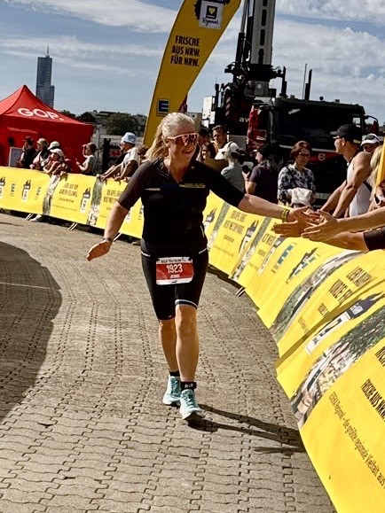 Jennie Schaaf vom PSV Brühl Triathlon Team mit Startnummer 1923 im Zieleinlauf des Köln Triathlon, sie schlägt in die Hände der Zuschauer ein