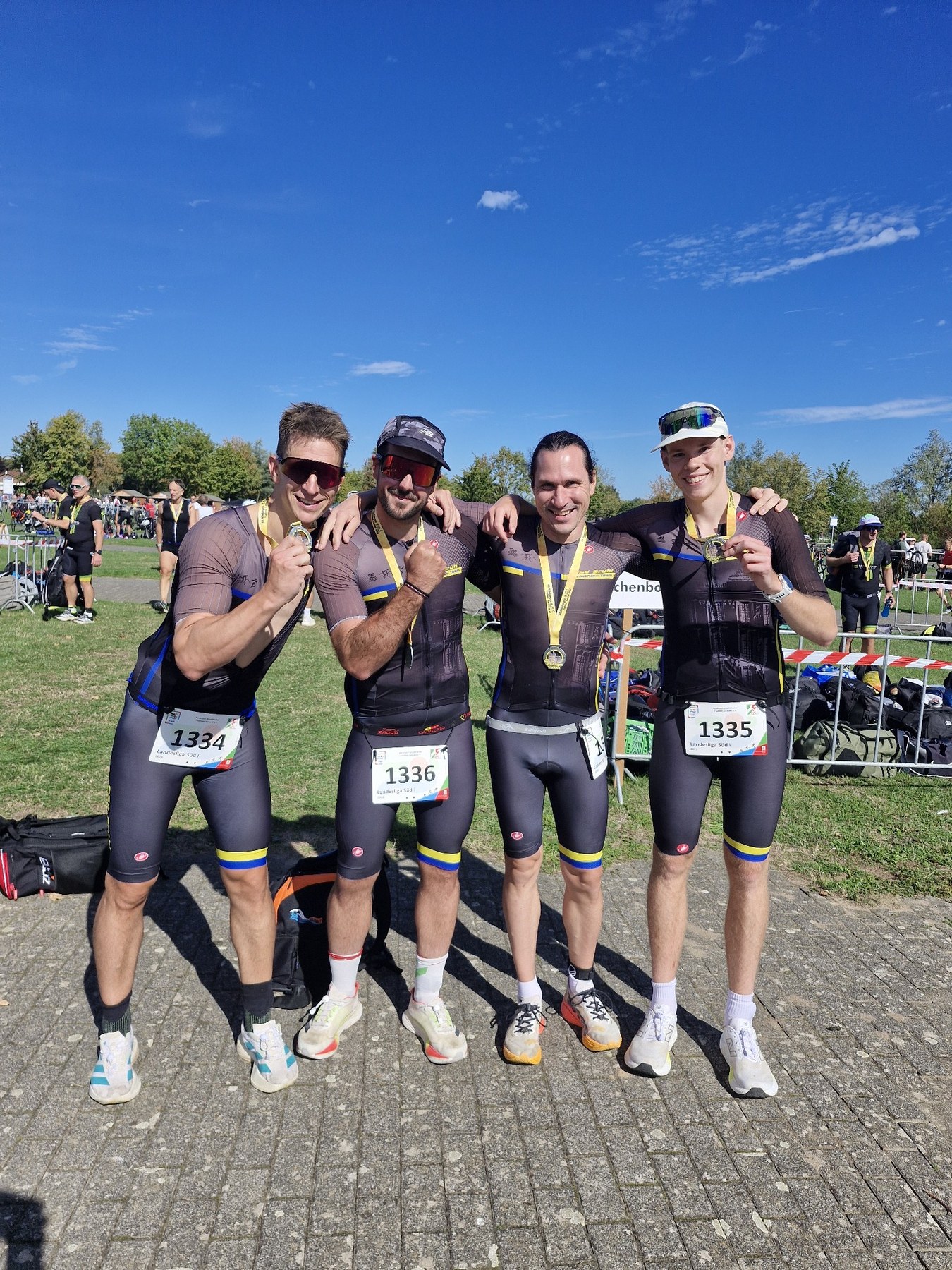 Vier Athleten des PSV Brühl Triathlon Team stehen mit Finisher-Medaillen und Startnummern 1334, 1336 und 1335 nebeneinander auf dem Wettkampfgelände in Xanten