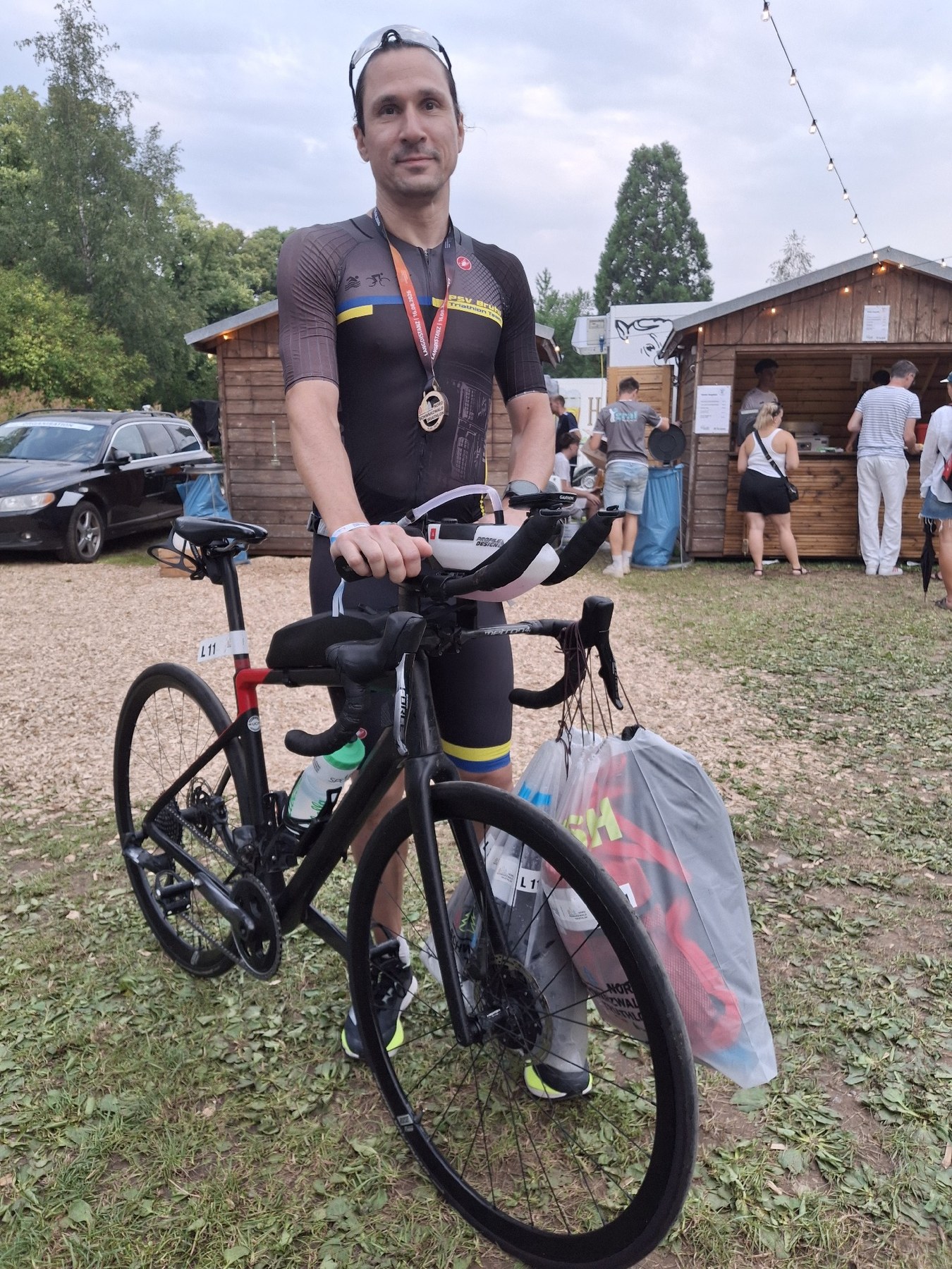 Björn Zeese vom PSV Brühl Triathlon Team steht nach dem Nordschwarzwald Triathlon mit Rad und Finisher-Medaille auf dem Veranstaltungsgelände
