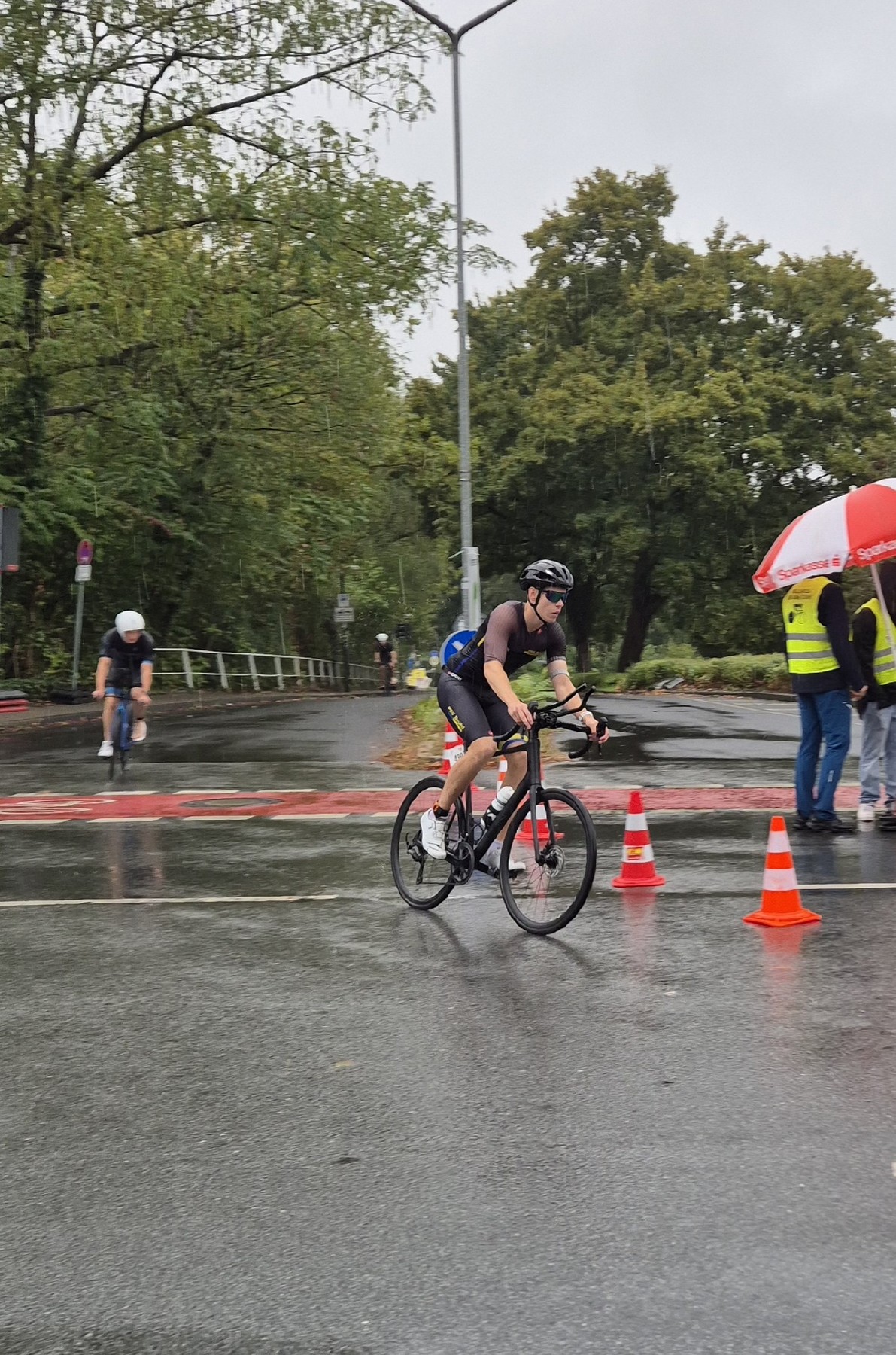 Athlet des PSV Brühl Triathlon Team auf dem Rad zwischen orangen Pylonen bei Regen in Ratingen